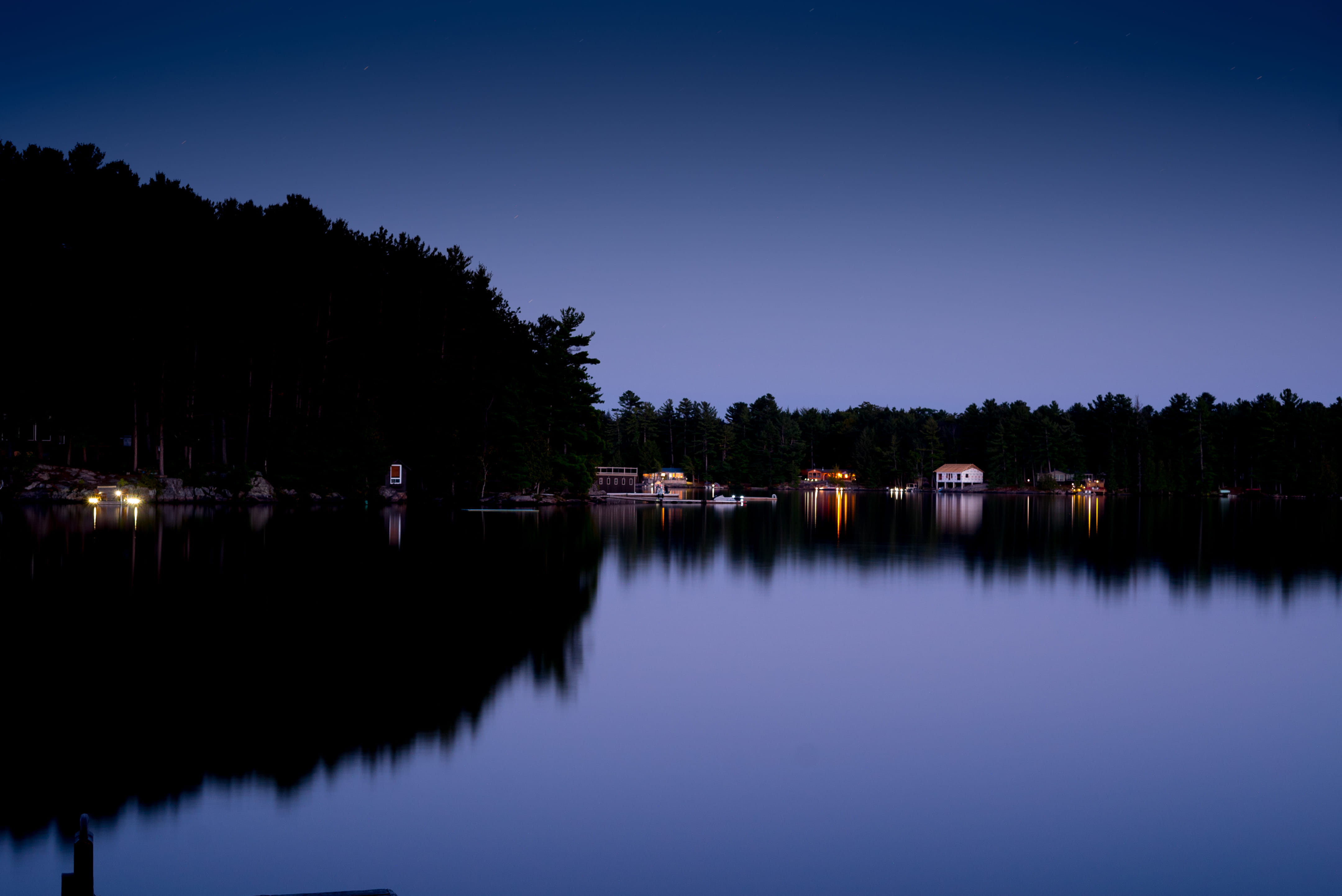 Lakefront cottages at dusk with warm lights reflecting on still water
